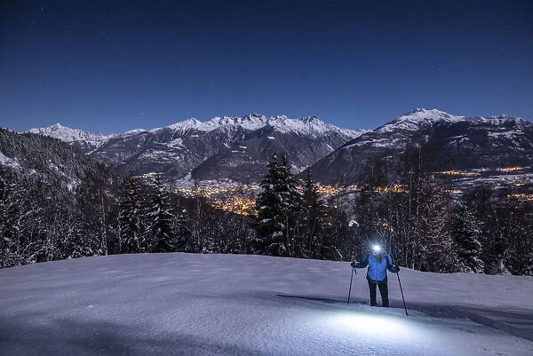 Young girl with snowshoes in a night with full moon, Piazzola alp