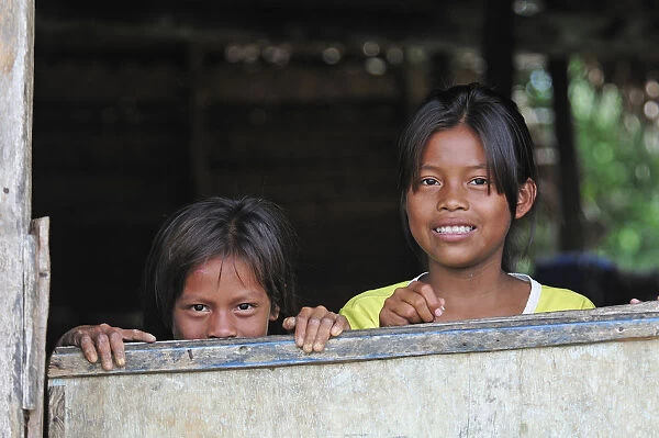 Two young girls looking out of a window, Amacayon Indian Village, Amazon river, Puerto