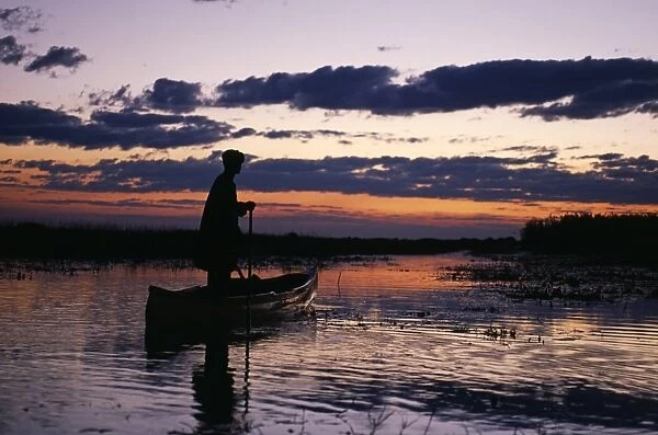Zambia Game scout poling mokorro along Lukulu River at sunset