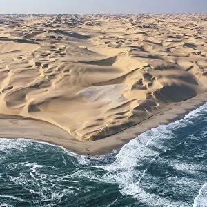 Aerial shot of the cold waters of the Atlantic Ocean meeting the sand dunes of the
