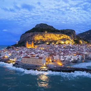 Aerial view of the illuminated Cefalu with the main cathedral and the rock behind the village, dusk time, Cefalu, Palermo province, Tyrrhenian sea, Sicily, Italy Aerial view of the illuminated Cefalu with the main cathedral and the rock behind the village, dusk time, Cefalu, Palermo province, Tyrrhenian sea, Sicily, Italy