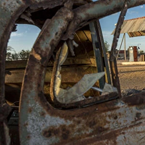 Africa, Namibia, Keetmanshop. Old petrol station seen through a rusty car door