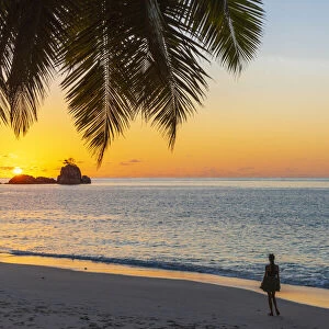 Africa, Seychelles, Mahe. Sunset at Anse Soleil Beach with a woman admiring the moment