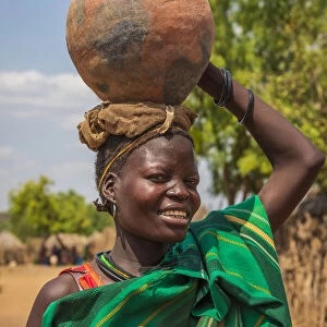 Africa, Uganda, Karamoja. Moroto. Portrait of a woman carrying a water jar at Nakapelimoru