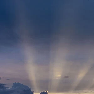 Africa, Zimbabwe, Hwange National Park. Sunbeams burst out above cumulus clouds at