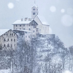 the ancient village of Colle Santa Lucia with the church on the hill under a snowfall
