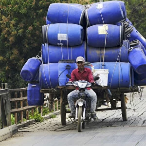 Asia, South East Asia, Cambodia, motorbike rider with a heavy load crossing a bridge