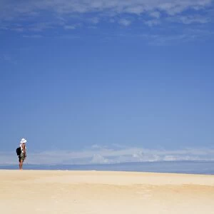 Australia, Tasmania, Strahan. A hiker looks out over Henty Dunes - a desert-like expanse of coastal sand dunes near