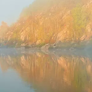 Autumn colors reflected in Lake Laurentian on an early foggy morning Sudbury, Ontario, Canada