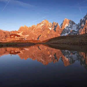 The Baita Segantini and the Pale di San Martino perfectly reflecting into a small lake at sunset. Dolomites, italy