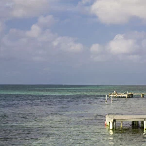 Belize, Tobaco Caye, Tourists sitting on pier reading