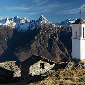 The bell tower of Alpe Scima, with Pizzo di Prata in the background, in winter