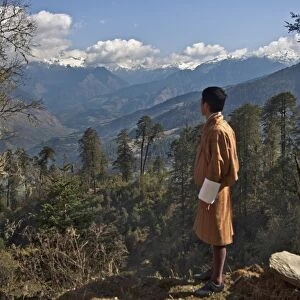 A Bhutanese man in national costume views an eastern Himalayan mountain range from the 11