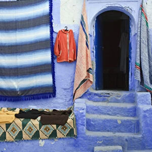 Blue doorway and traditional Moroccan fabrics, Chefchaouen, Morocco