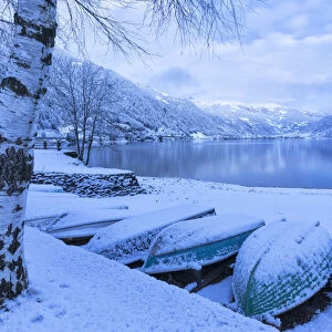 Boats covered by snow at Poschiavo Lake during twilight. Poschiavo Lake, Poschiavo Valley(Val Poschiavo), Graub√ºnden, Switzerland