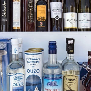 Bottles of traditional Ouzo liquor and local Greek wines on sale in a shop of Oia