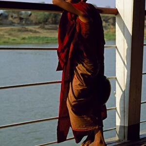 A boy monk gazing out over the rails of a boat on the Irrawaddy River