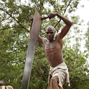 Burundi. A man cuts a tree into planks in a traditional sawpit