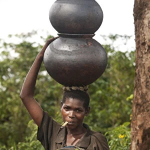 Burundi. A woman uses traditional pots to transport her goods to market