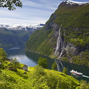 A car ferry passes beneath an old abandoned farm & the Seven Sisters waterfall, Geiranger