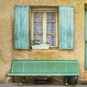 Cat sleeping under a bench in front of a house in Roussillon, Vaucluse
