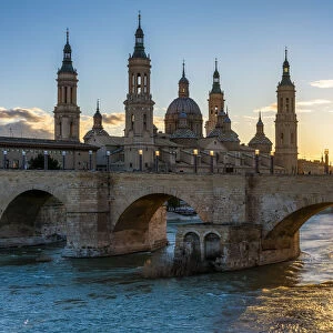 Cathedral of Our Lady of the Pillar and stone bridge at sunset. Zaragoza, Aragon, Spain