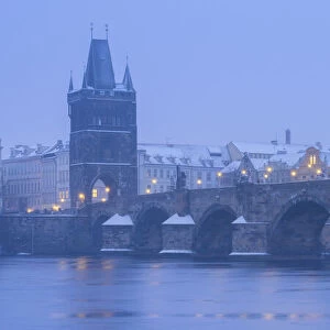 Charles Bridge and Old Town Bridge Tower against snowy sky in winter, Prague, Bohemia