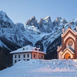 The church of Falcade, with Focobon peaks in the background, in wintertime, Dolomites