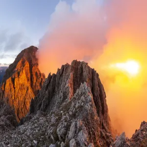 Cloudy sunset with Roda de Vael peak illuminated and backlight red clouds from the rocks