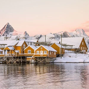 The colors of dawn frames the fishermen houses surrounded by snowy peaks Sakrisoy