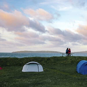 A couple enjoying the sunset in a camping site in Torshavn. In the background the island of Nolsoy