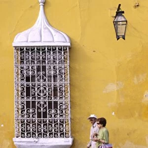 A couple pass a colonial mansion on the Plaza de Armas in Trujillo