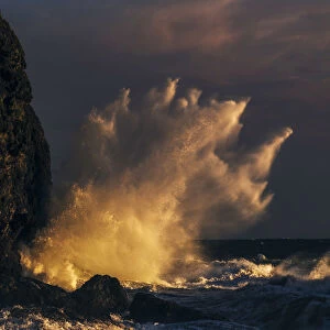 Crushing wave over the coast at sunset, Tuscany, Italy