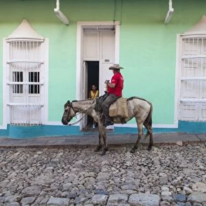 Cuba, Trinidad, Milkman on horseback delivers bottles of milk to house