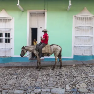 Cuba, Trinidad, Milkman on horseback delivers bottles of milk to house