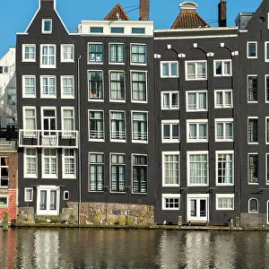 Dancing houses near river against sky, Damrak, Amsterdam, Netherlands