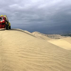 A dune buggy on the sand dunes bordering the city of Ica