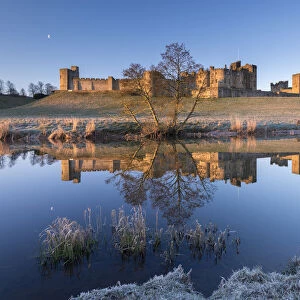 Early morning sunshine illuminates Alnwick Castle in Northumberland, England. Winter