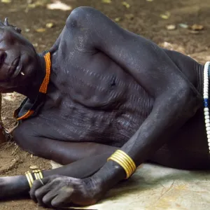 An elder of the Karo tribe rests with his head on his