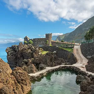 Elevated view of couple swimming in natural volcanic rock pools near Aquarium of Madeira (Aquario da Madeira), Porto Moniz, Madeira, Portugal