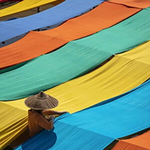 Elevated view of woman hanging long pieces of dyed fabric to dry, Lake Inle