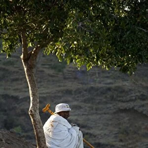 Ethiopia, Lalibela. An old man rests beneath a tree in the early morning light