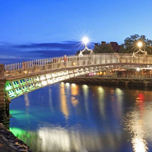 Europe, Dublin, Ireland, Halfpenny bridge reflecting on the Liffey river by night