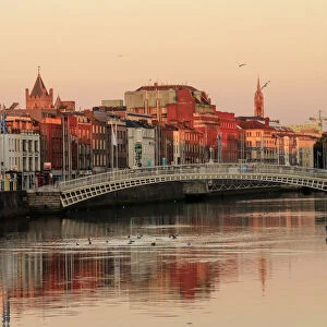 Europe, Dublin, Ireland, Halfpenny bridge at sunrise with buildings reflecting in