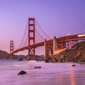 Famous Golden Gate Bridge over bay against purple sky during sunset, San Francisco