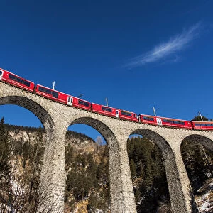 The famous red train of Albula mountain railway while passing on the Landwasser viaduct