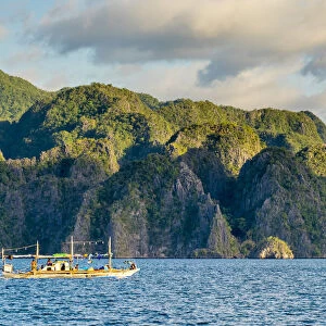 Filipino outrigger fishing boat and dramatic karst landscape of Coron Island, Palawan
