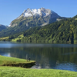 Fisherman at Lake Wagital with Fluebrig mountain in the Glarner Alps at fall
