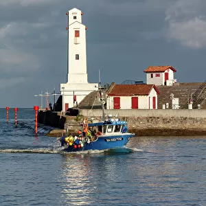 A fishing boat passes the lighthouse at Saint-Jean-de-Luz, Pyrenees-Atlantiques, Nouvelle Aquitaine, France