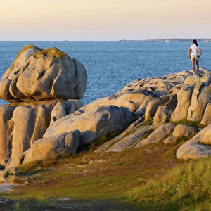 France, Brittany, Finistere, Cleder, woman standing on granite rocks (MR)